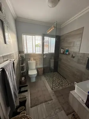 a bathroom with a shower and a toilet and a sink at Strand Holiday home in Cape Town