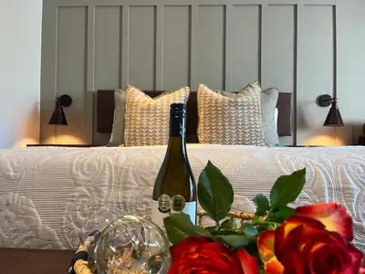 a bottle of wine on a table next to a bed at The Cliff Villa Boutique Guesthouse in Hermanus