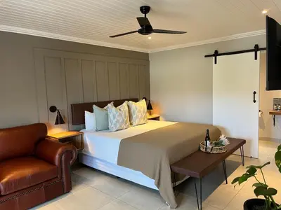 a bedroom with a large bed and a chair at The Cliff Villa Boutique Guesthouse in Hermanus