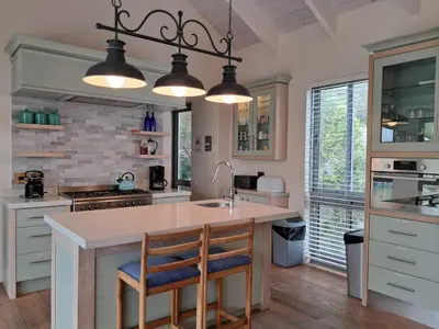 a kitchen with white cabinets and a island with a sink at Knight's House 6 sleeper in Hermanus