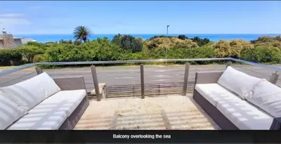 a couch on a balcony with a view of the ocean at Knight's House 6 sleeper in Hermanus