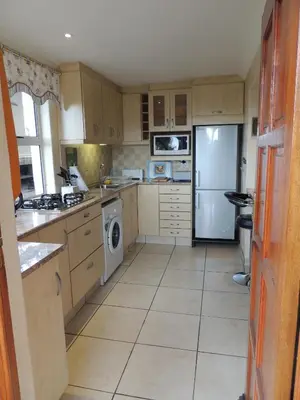 a kitchen with wooden cabinets and a white refrigerator at 8 on Lily Self catering in Cape Town