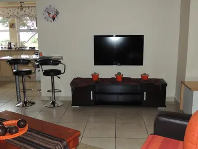 a living room with a flat screen tv on a wall at 8 on Lily Self catering in Cape Town