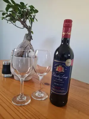 a bottle of wine and two wine glasses on a table at H & E Sunset Paradise in Fisherhaven