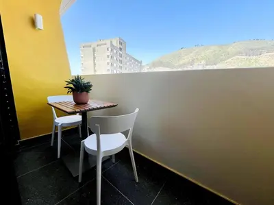 a table with two chairs and a potted plant on a balcony at Seapoint Solace in Cape Town