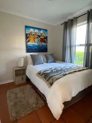 a bedroom with a large bed with a painting on the wall at The Hermanus holiday self catering beach club in Hermanus