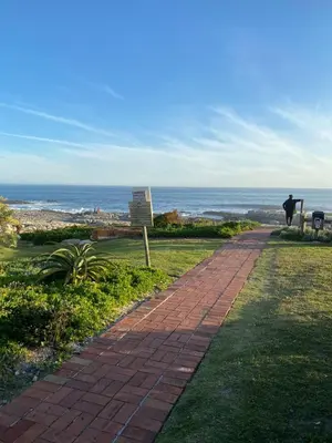 a man walking down a brick path near the ocean at The Hermanus holiday self catering beach club in Hermanus