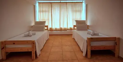 two beds in a room with a window at Montana Backpackers Cape Town in Cape Town
