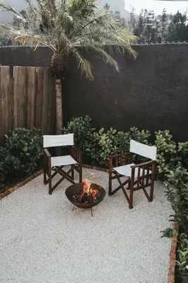 two benches and a fire pit in a backyard with a palm tree at No 3 at The Barracks in Stellenbosch