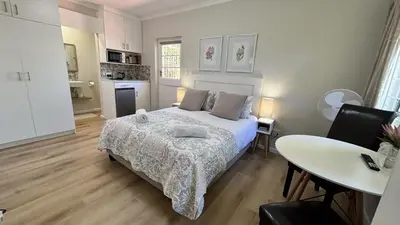 a bedroom with a bed and a table and a kitchen at Paradysrus in Stellenbosch