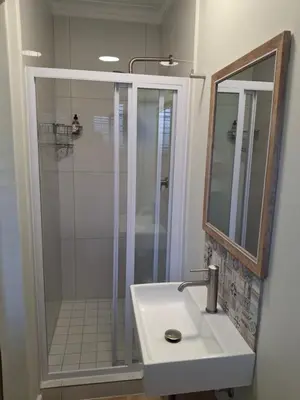 a bathroom with a shower and a sink and a mirror at Paradysrus in Stellenbosch