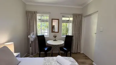 a bedroom with a bed and a table and chairs at Paradysrus in Stellenbosch