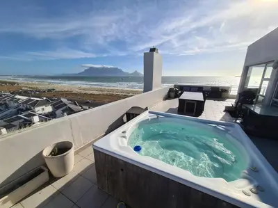 a jacuzzi tub on a balcony with the beach at Jacuzzi with 270 views right on beach in Cape Town