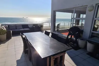 a table on a balcony with a view of the ocean at Jacuzzi with 270 views right on beach in Cape Town