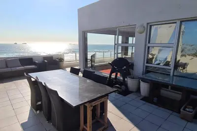 a table and chairs with a view of the ocean at Jacuzzi with 270 views right on beach in Cape Town