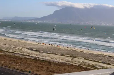 a beach with people flying kites in the ocean at Jacuzzi with 270 views right on beach in Cape Town