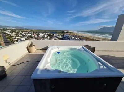 a bath tub sitting on top of a balcony with the beach at Jacuzzi with 270 views right on beach in Cape Town