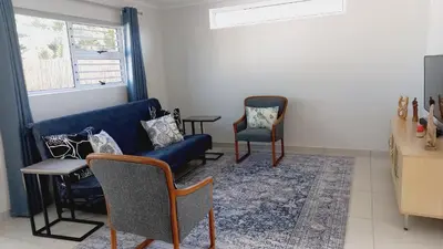 a living room with a blue couch and two chairs at Pet friendly & Close to Beach at 2 Saasveld in Bloubergstrand