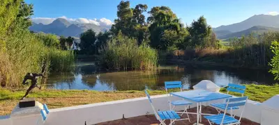 a table and chairs and a statue next to a river at Whipstock Guest Farm in McGregor