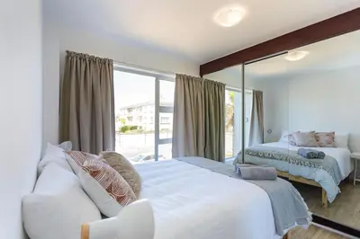 a bedroom with two beds and a large mirror at Ocean View B104 by CTHA in Bloubergstrand