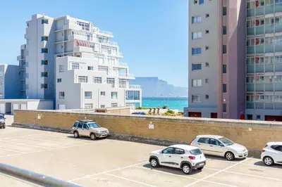 a group of cars parked in a parking lot in front of buildings at Ocean View B104 by CTHA in Bloubergstrand