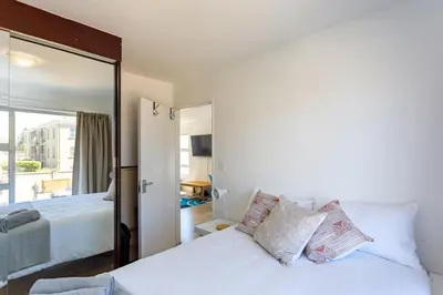 a bedroom with a white bed and a mirror at Ocean View B104 by CTHA in Bloubergstrand