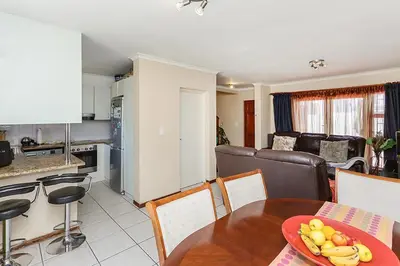 a kitchen and a living room with a table and chairs at Secured 3-Bedroom Townhouse in Cape Town