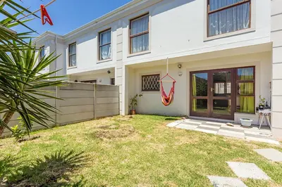 a white house with a fence and a yard at Secured 3-Bedroom Townhouse in Cape Town