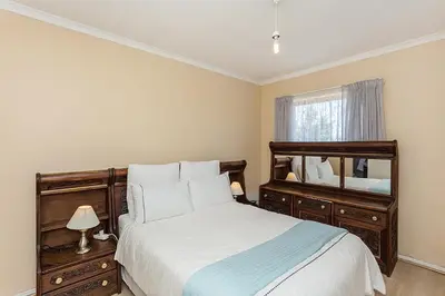a bedroom with a large bed and a mirror at Secured 3-Bedroom Townhouse in Cape Town