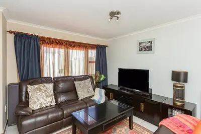a living room with a leather couch and a television at Secured 3-Bedroom Townhouse in Cape Town