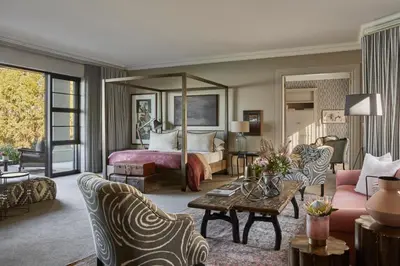 a bedroom with a bed and a living room at The Thatch House Boutique Hotel, Hermanus in Hermanus
