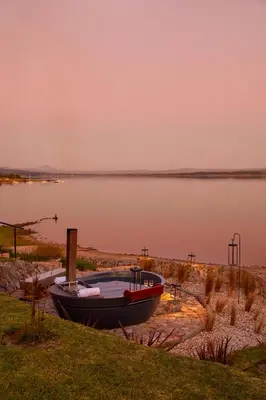 a boat sitting on the shore of a lake at The Thatch House Boutique Hotel, Hermanus in Hermanus