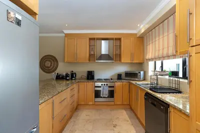 a kitchen with wooden cabinets and granite counter tops at Pearl Valley Golf Estate Lodge 1E in Simondium