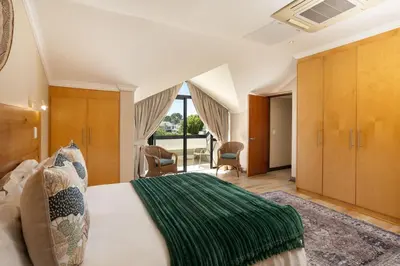 a bedroom with a large bed with a green blanket at Pearl Valley Golf Estate Lodge 1E in Simondium