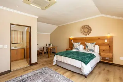 a bedroom with a large bed and a bathroom at Pearl Valley Golf Estate Lodge 1E in Simondium