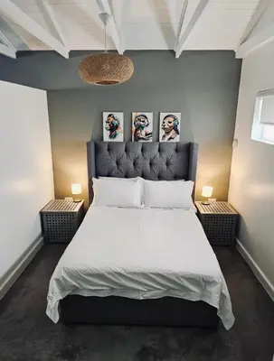 a bedroom with a large white bed with two lamps at Blouberg Rise Cottage in Cape Town