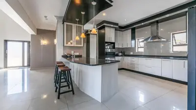 a kitchen with white cabinets and a black counter top at Paraiso - A cozy retreat , your home away from home in Cape Town