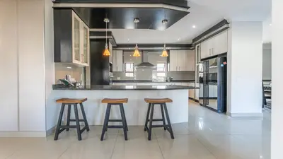 a kitchen with two bar stools and a counter at Paraiso - A cozy retreat , your home away from home in Cape Town