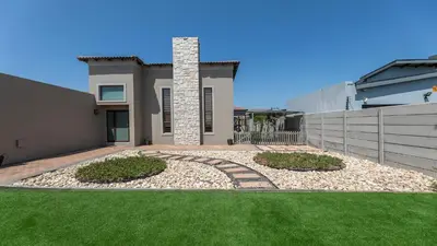 a house with a fence and a grass yard at Paraiso - A cozy retreat , your home away from home in Cape Town