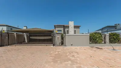 a house with a gate and a brick driveway at Paraiso - A cozy retreat , your home away from home in Cape Town