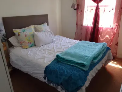 a bed with white sheets and pillows and a window at Nortey is palace in Cape Town