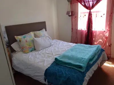 a bedroom with a bed with pillows and a window at Nortey is palace in Cape Town