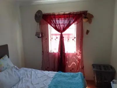 a bedroom with a red curtain and a window at Nortey is palace in Cape Town