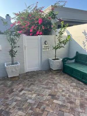 a patio with two potted plants and a bench at On Musson in Hermanus