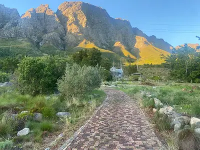 a brick road in a field with mountains in the background at Stonehedge Cottages in Franschhoek