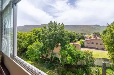 a window with a view of trees and mountains at Oak Terrace 28 in Hermanus