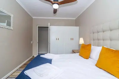 a bedroom with a large white bed with orange pillows at Oak Terrace 28 in Hermanus