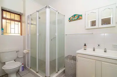a bathroom with a shower and a toilet and a sink at Oak Terrace 28 in Hermanus