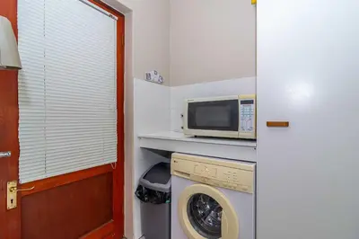 a laundry room with a microwave and a washing machine at Oak Terrace 28 in Hermanus