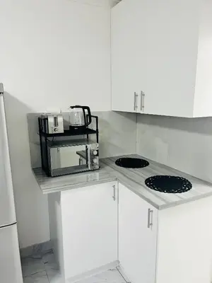 a kitchen with white cabinets and a microwave on a counter at Self catering one bedroom cottage in Cape Town
